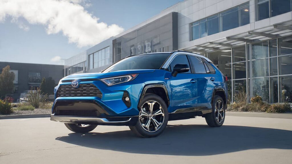 A 2026 Toyota RAV4 Hybrid being charged at a public station near a modern shopping center