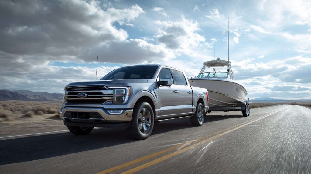 2026 Ford F-150 PowerBoost Hybrid towing a boat trailer on a wide Texas highway