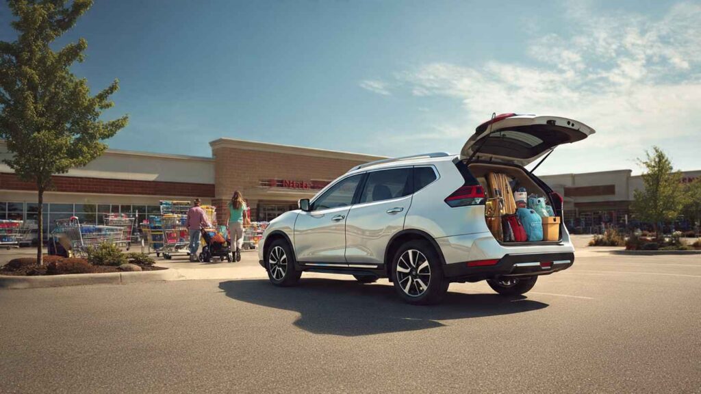 2026 Nissan Rogue in a suburban parking lot with family loading cargo