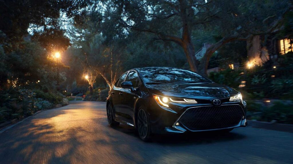 2026 Toyota Corolla Hybrid in Midnight Black driving on a suburban street at dusk